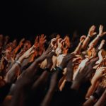 a crowd of people raising their hands in the air