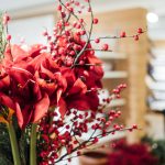 a vase filled with red flowers and greenery