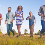 people running on grassfield under blue skies at daytime
