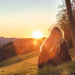 woman sitting on green grass looking at the sun