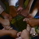 man in white t-shirt holding babys hand