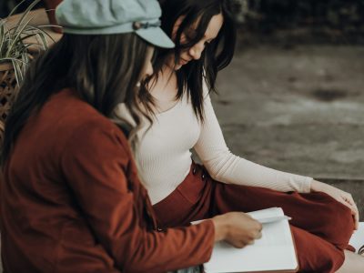 woman in white tank top and orange jacket holding white printer paper