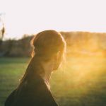 woman in black top looking toward sun during daytime