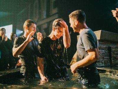 three men standing on black tub full of water