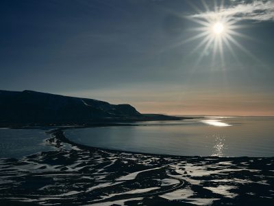 the sun is shining over the water and sand