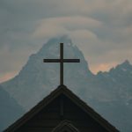 Cross atop church against misty mountains