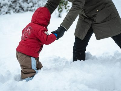 a man holding a child's hand in the snow